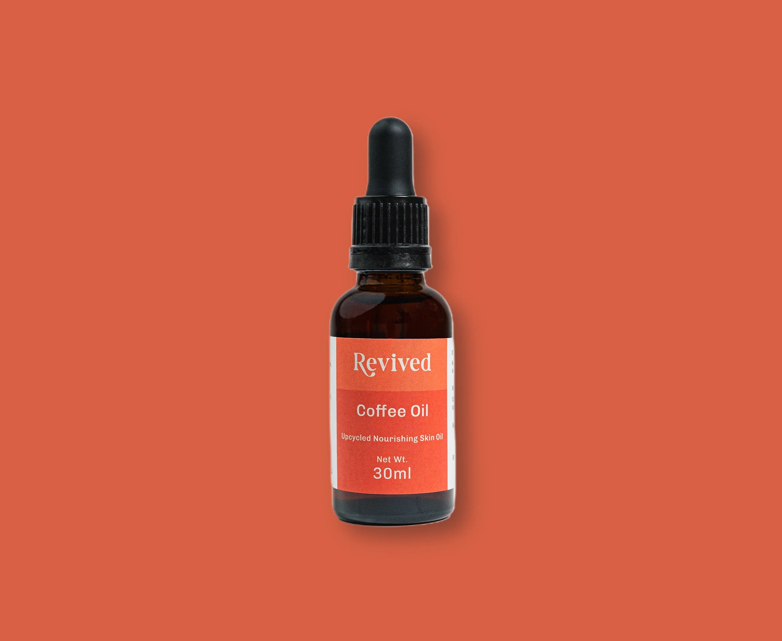 Bottle of Revived Coffee Oil on a solid terracotta background