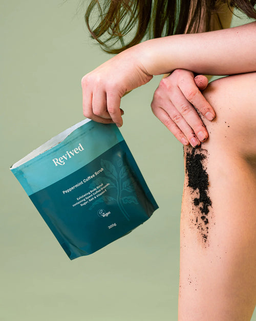 Person using Revived Peppermint Coffee Scrub on their skin with a green background