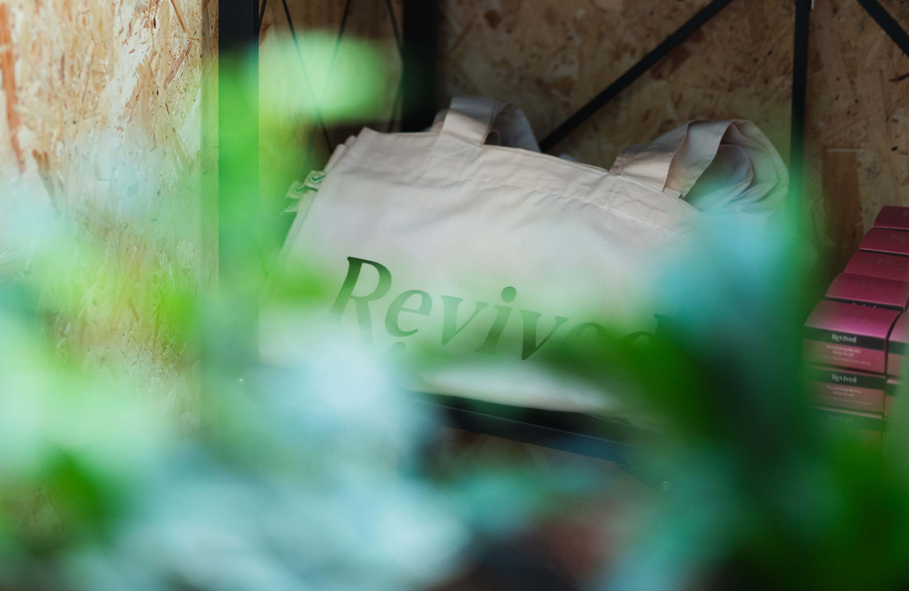 Revived products on shelf with chipboard backdrop and soft-focus plants in foreground