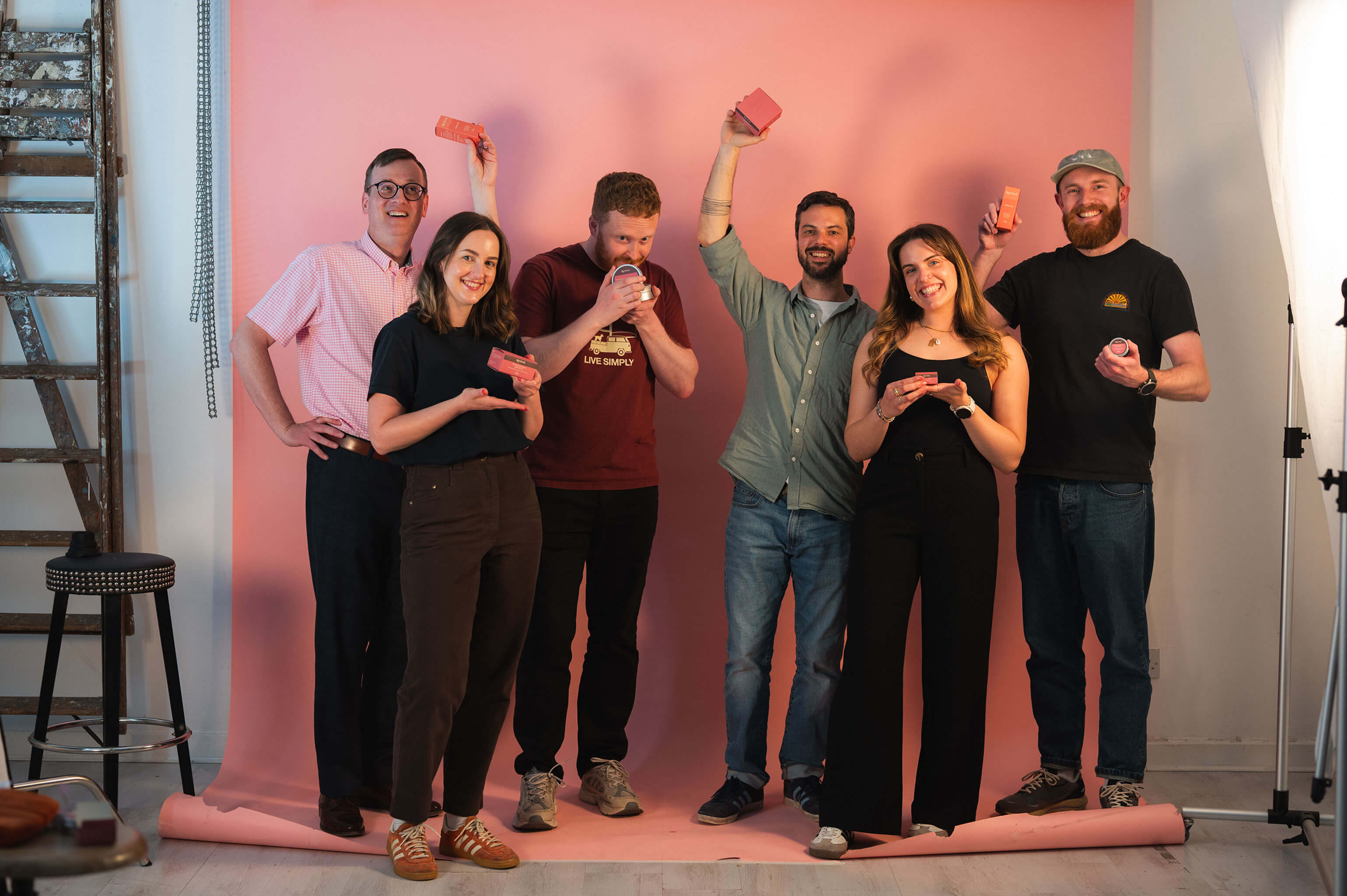 Six people posing with Revived products against pink studio backdrop