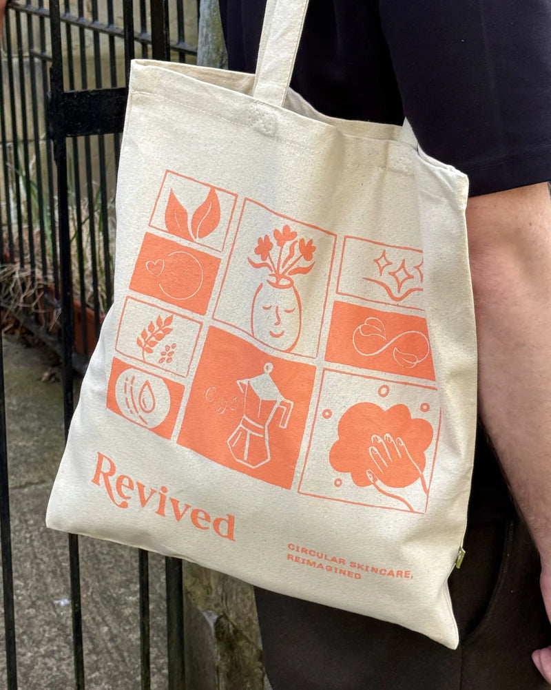 Revived Tote bag with orange mosaic design held by a person outdoors.