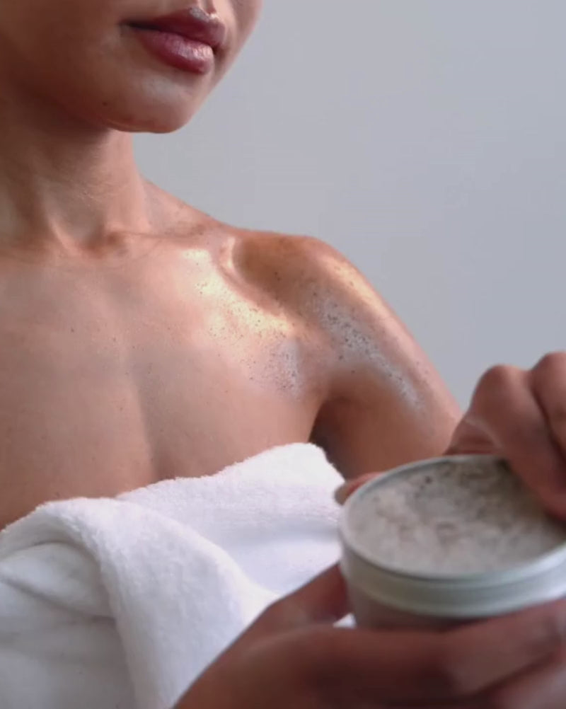 a model uses Revived mocha body scrub to exfoliate here shoulder