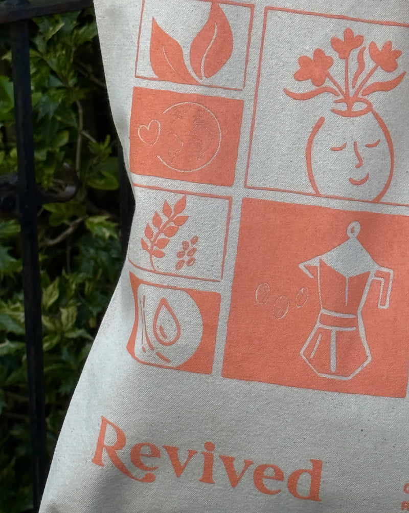 Decorative tote bag with orange mosaic and 'Revived' text on a beige background